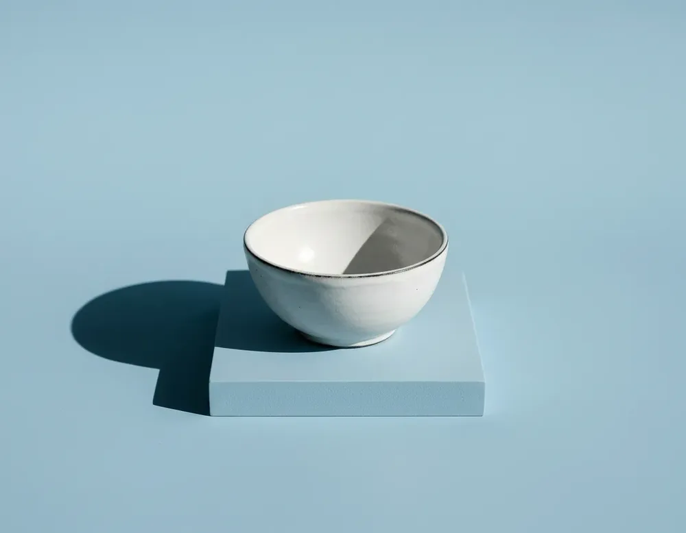 A white ceramic bowl on a pale blue block, from above